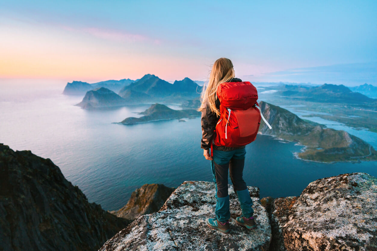 Woman wearing a red backpack, looking at mountains