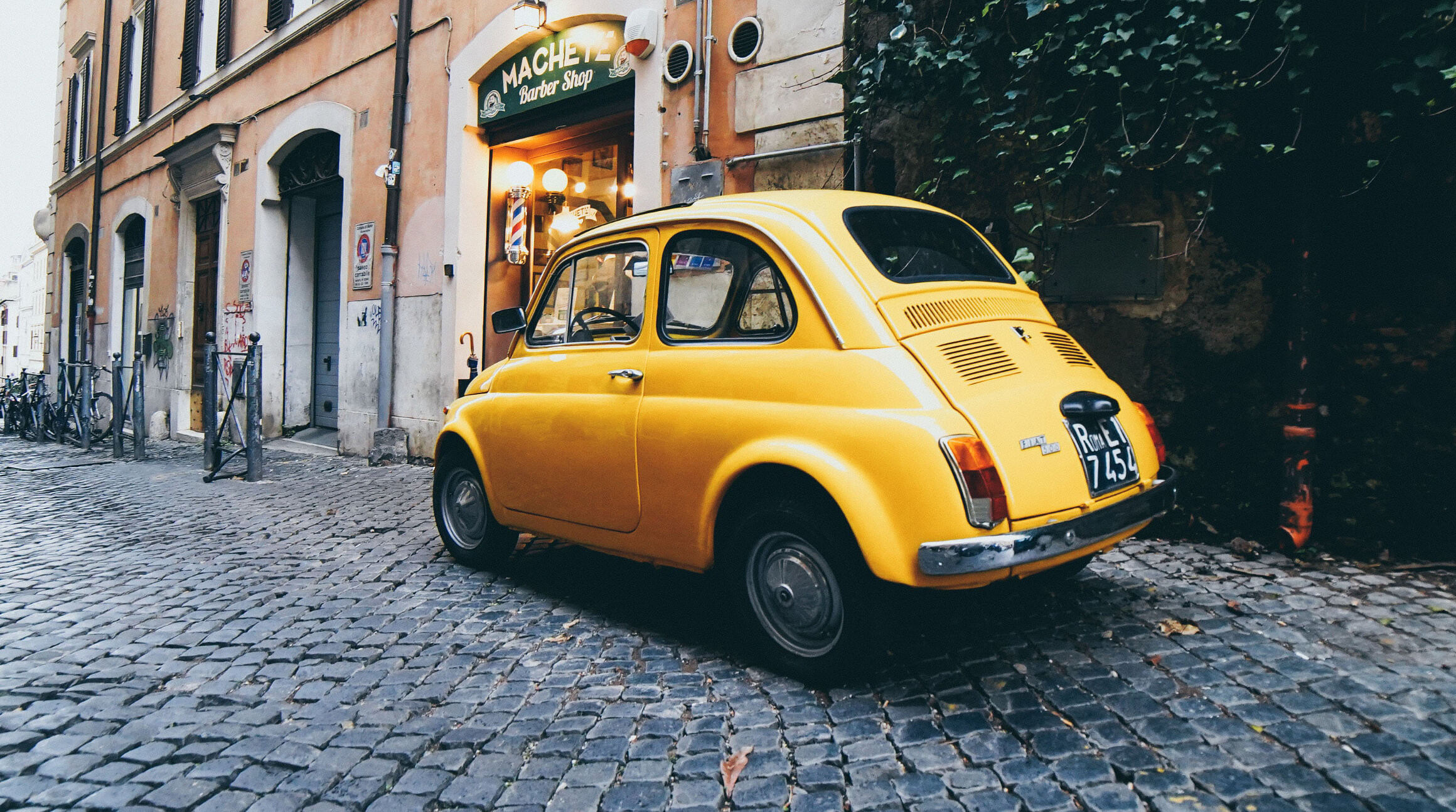 Yellow car driving on cobblestone street in Italy