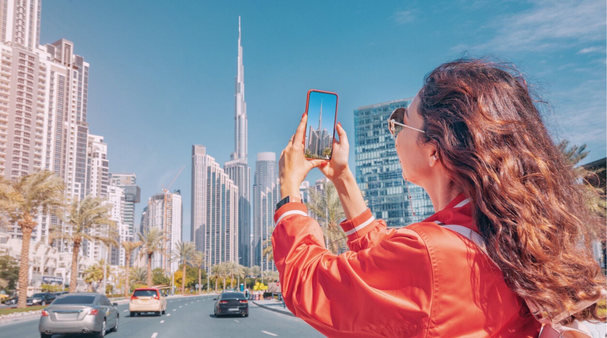 Una chica tomando fotos del Burj Khalifa en Dubái con su teléfono.