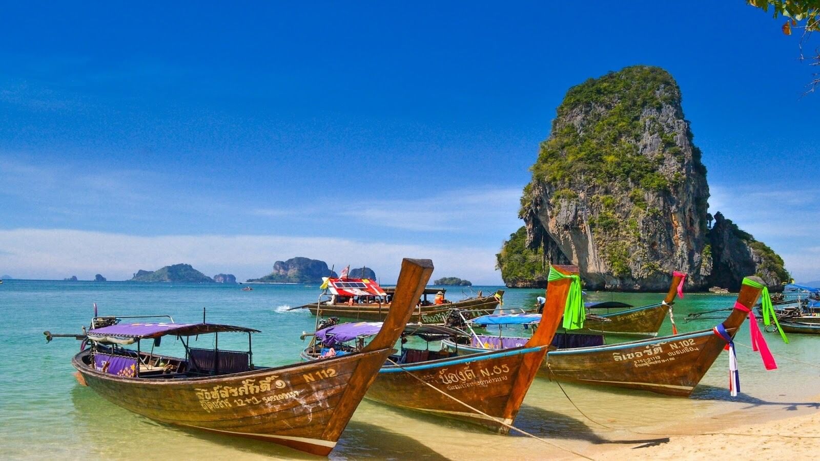 Five brown wooden boats in a beach with mountains in a distance during daytime