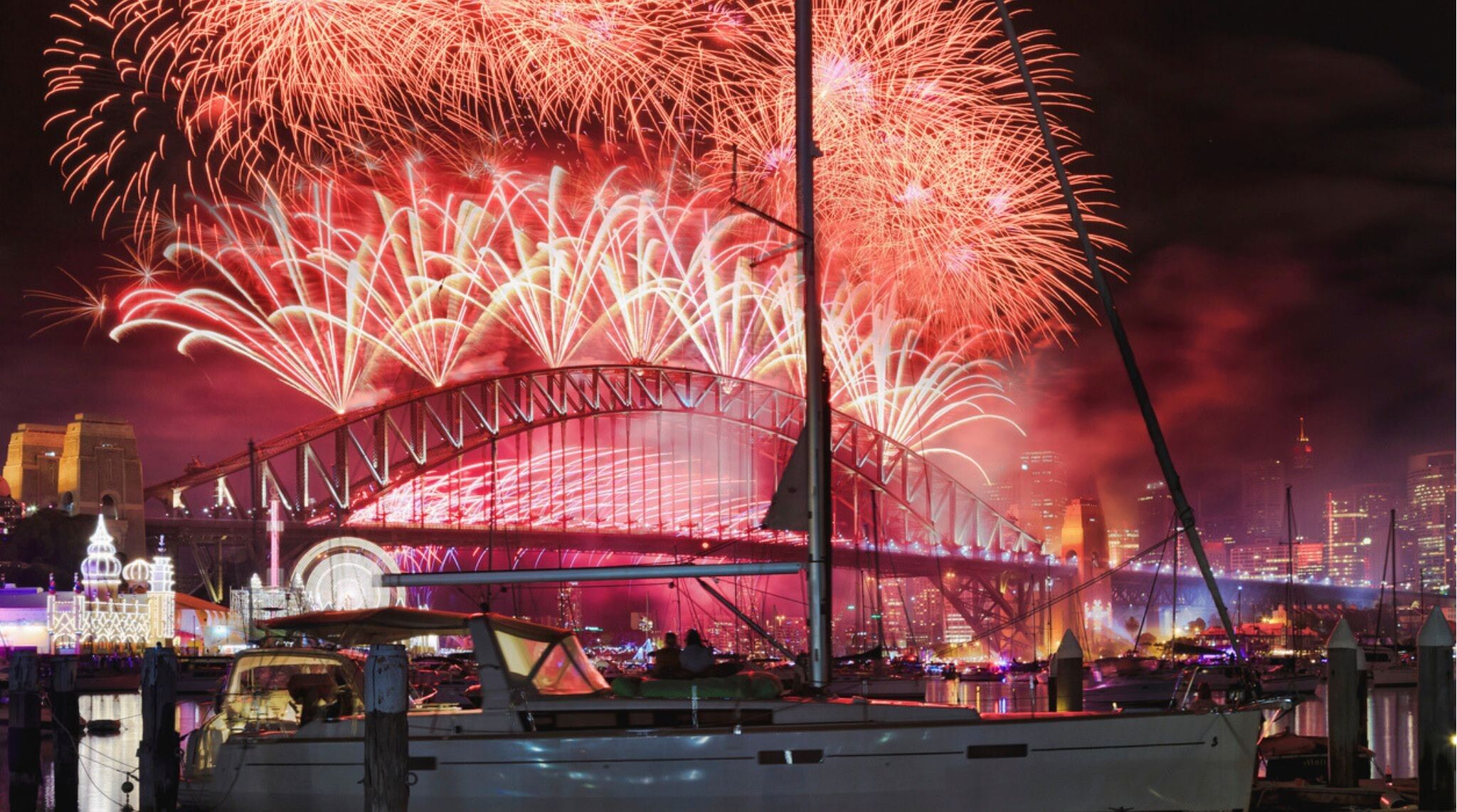 Vista aproximada dos fogos de Ano Novo de Sydney sobre a Sydney Bridge e o porto, vistos da baía de Lavender.