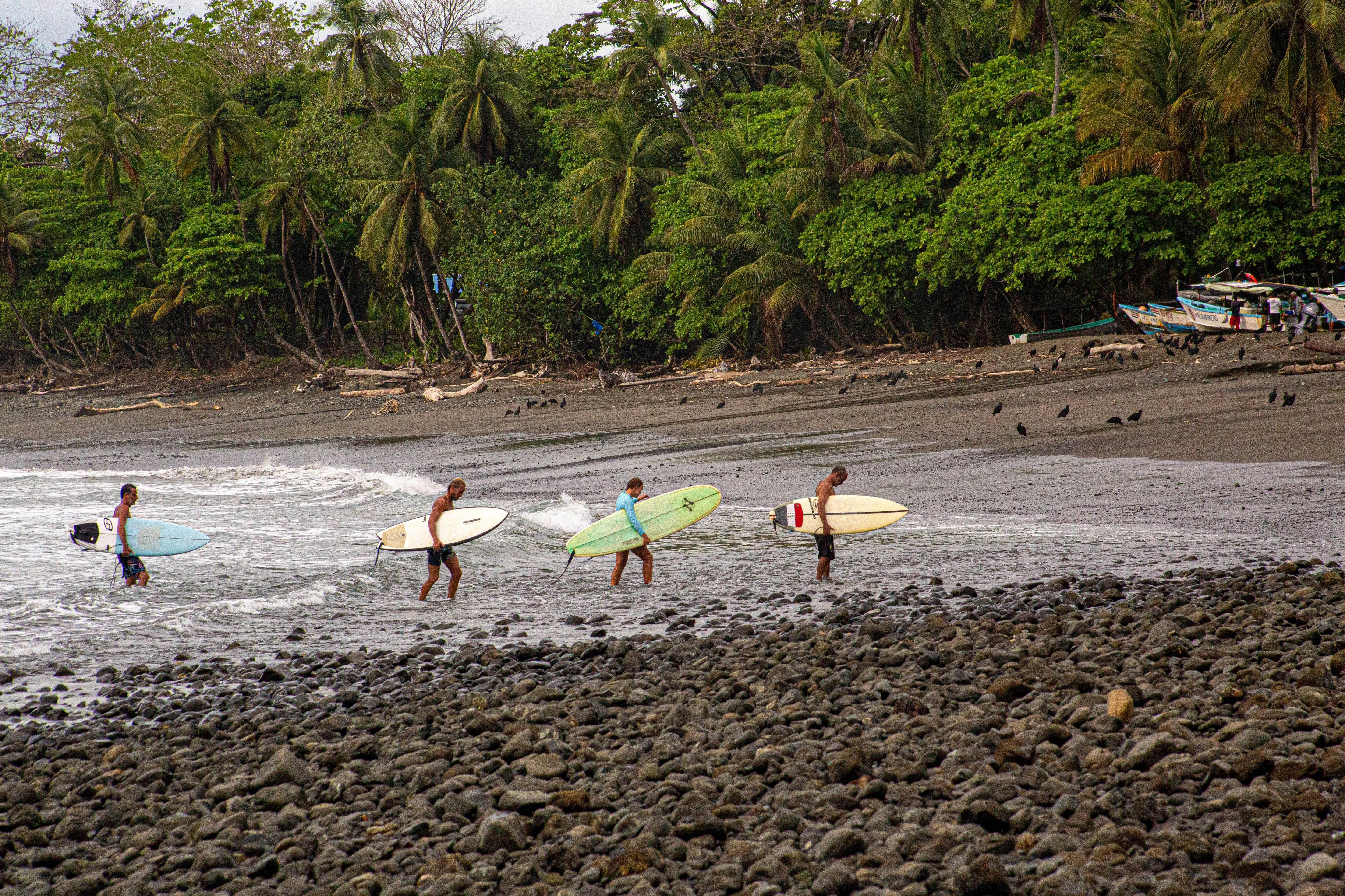 4 people holding surfboards on a beach in Costa Rica​​