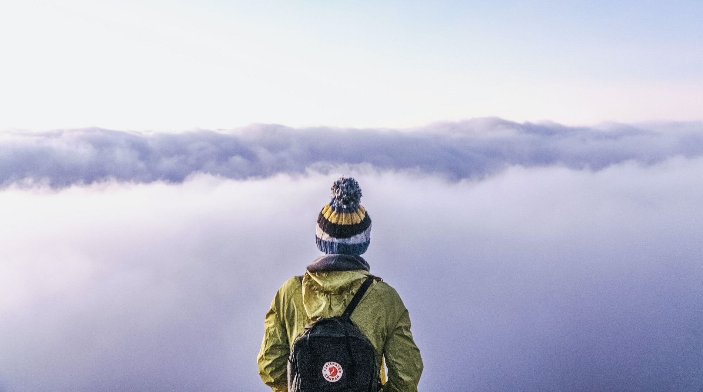 traveler standing on a mountaintop and looking out over the clouds