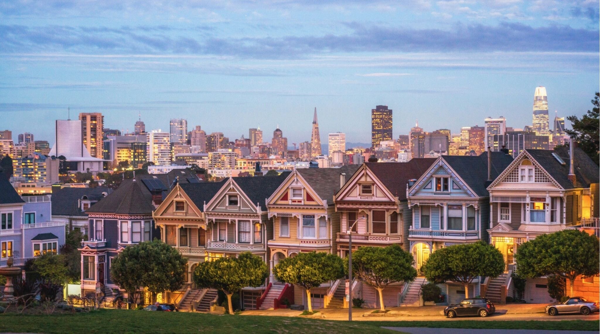 Casas victorianas Painted Ladies frente al skyline de San Francisco al atardecer.