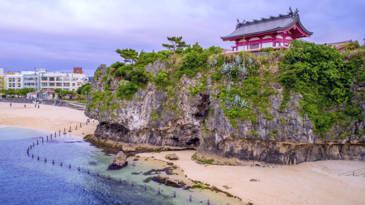 A colour photograph of Naminoue Shrine, a historic Shinto shrine in Naha, Okinawa, which sits on a cliff overlooking Naminoue Beach and the ocean. to illustrate a blog post entitled 'Top things to do in Okinawa, Japan's Tropical gem.'
