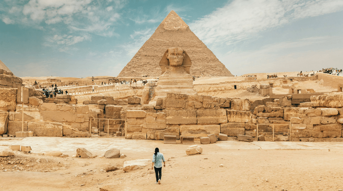 Man standing in front of the Sphinx and Pyramids of Giza