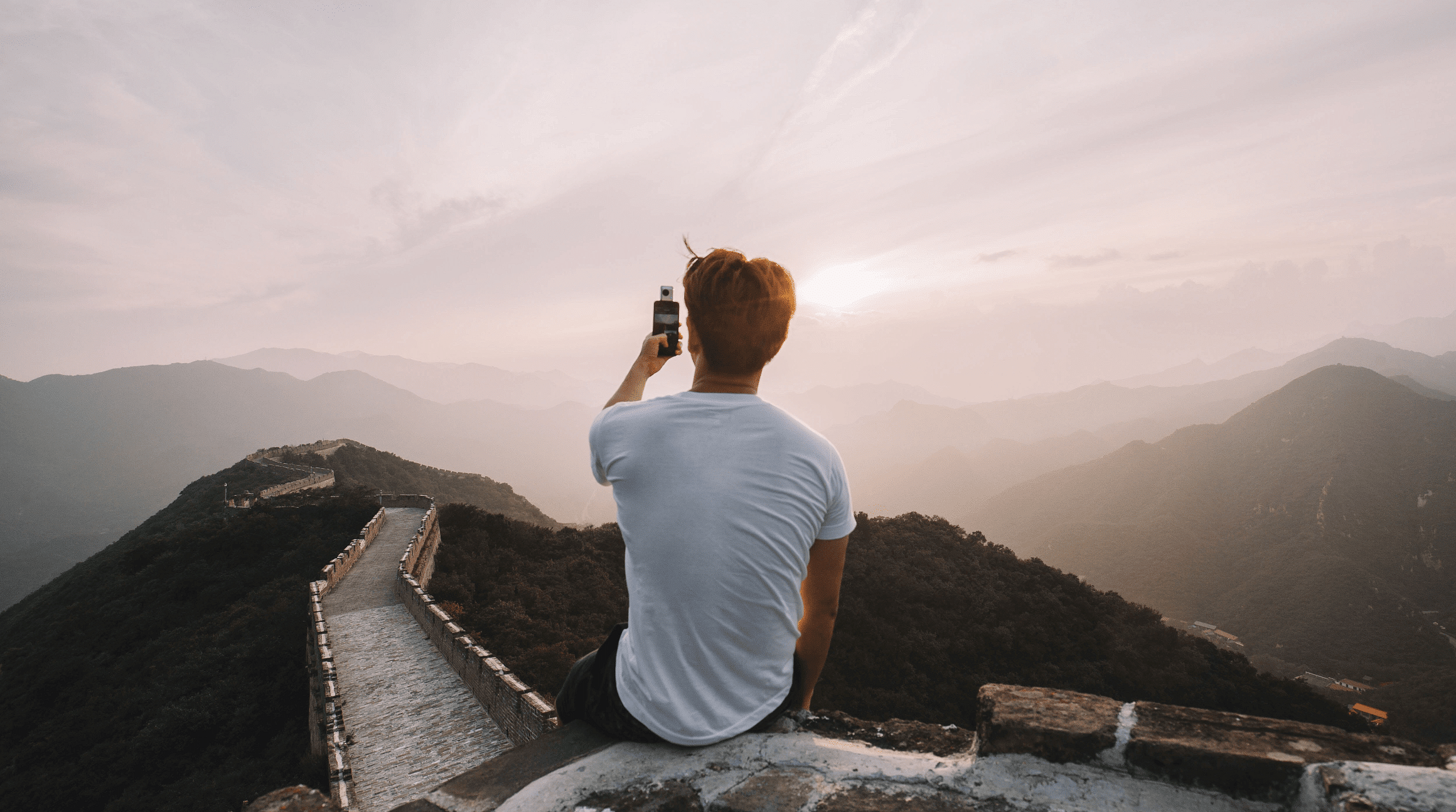 man taking a photo of the Great Wall at sunrise with his iPhone