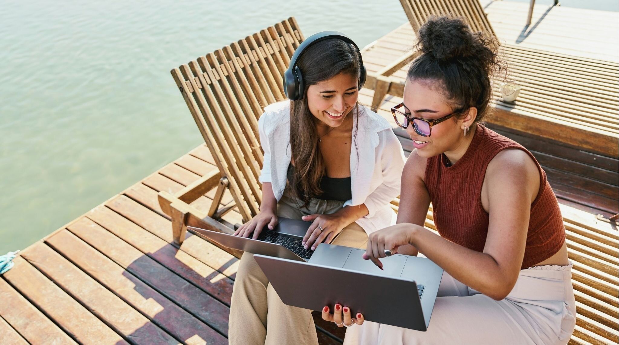 Par de mulheres sentadas em um deck de madeira.