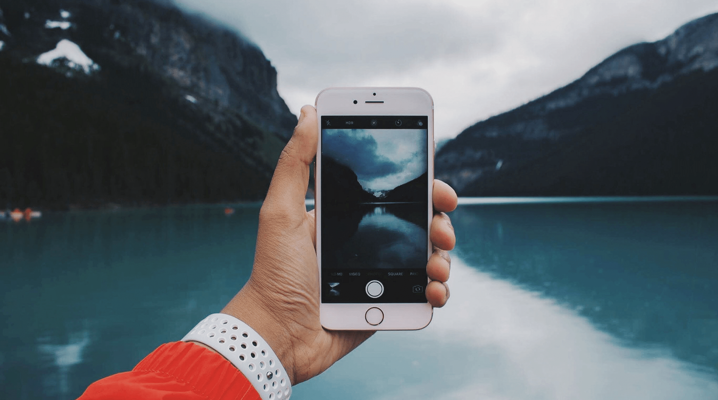 person taking a photo of a lake with an iPhone