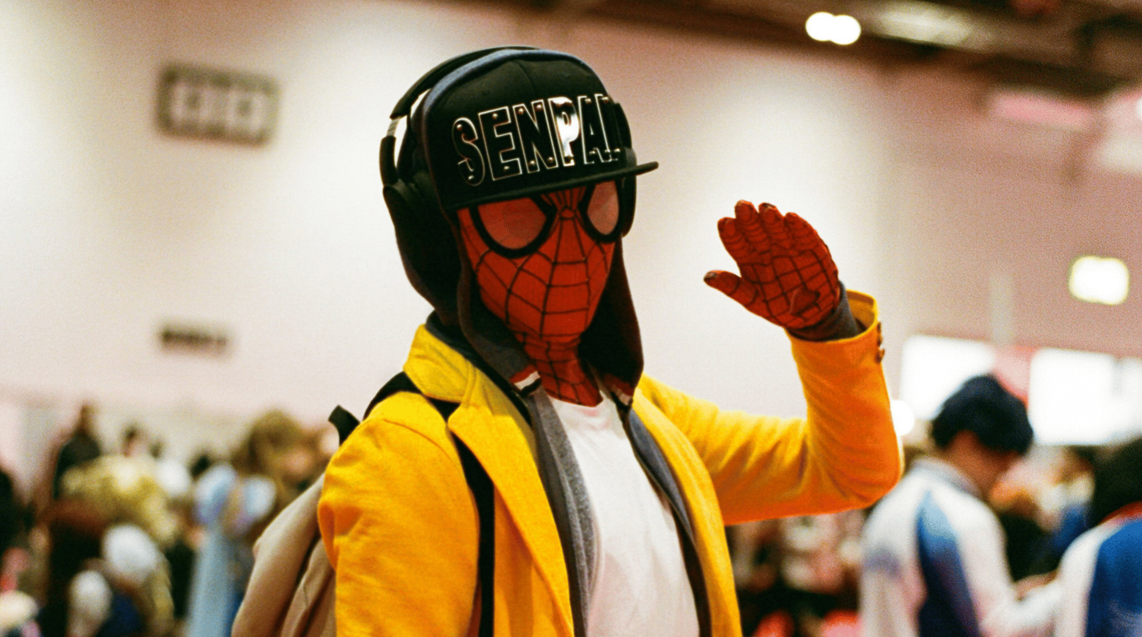 A colour photograph of an attendee of New York Comic Con, wh is dressed as Spiderman in a red mask with black webs overlaid, to illustrate a blog post entitled 'New York Comic Con 2025: A Complete Travel Guide for Attendees.'