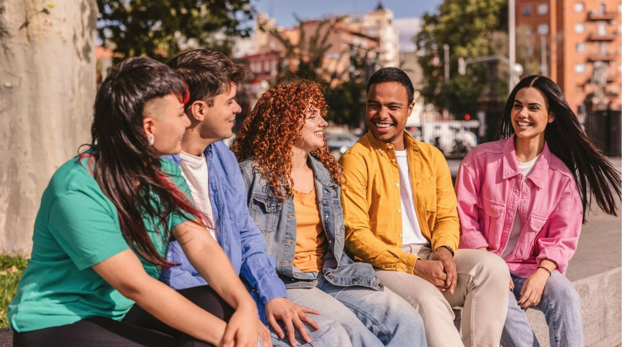 Grupo de amigos charlando en un parque de Madrid en un día soleado.