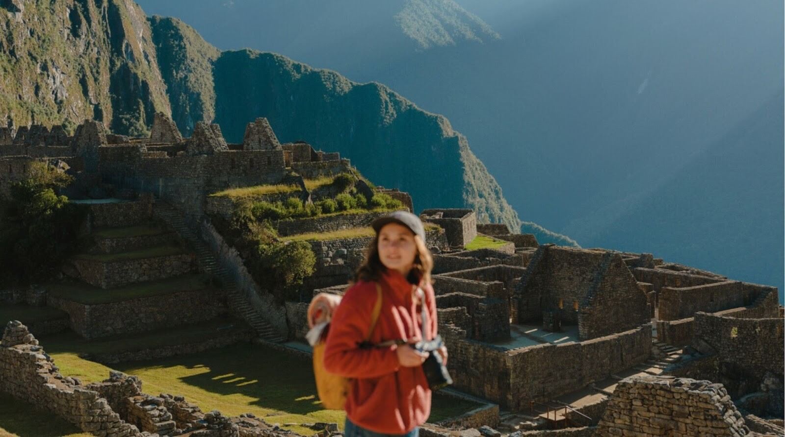 Mulher serena com mochila contemplando a vista panorâmica de Machu Picchu, no Peru.