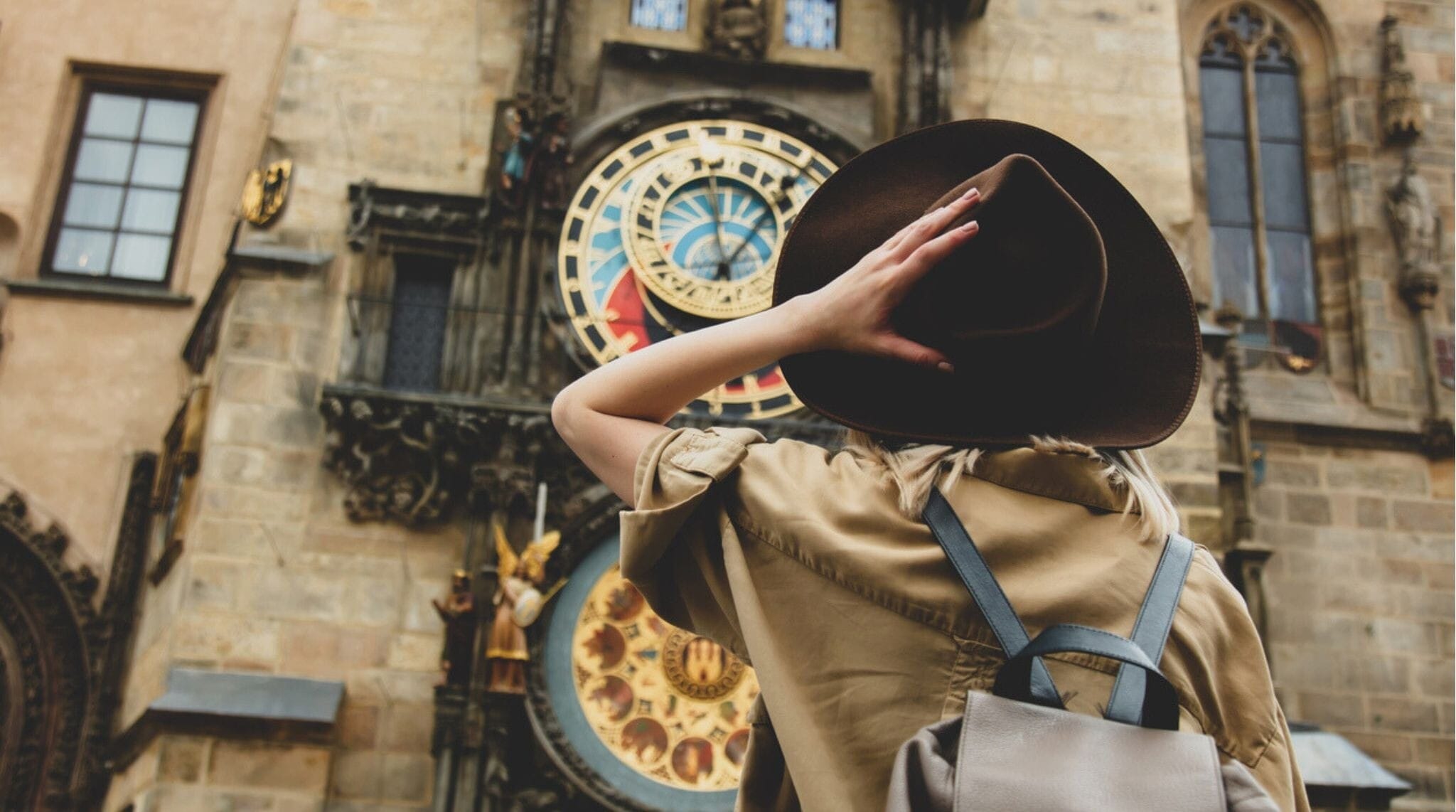 Garota loira com chapéu e mochila perto do famoso relógio em Praga, República Tcheca.