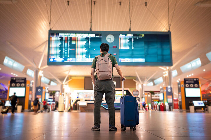 Man standing alone at the airport with his suitcase