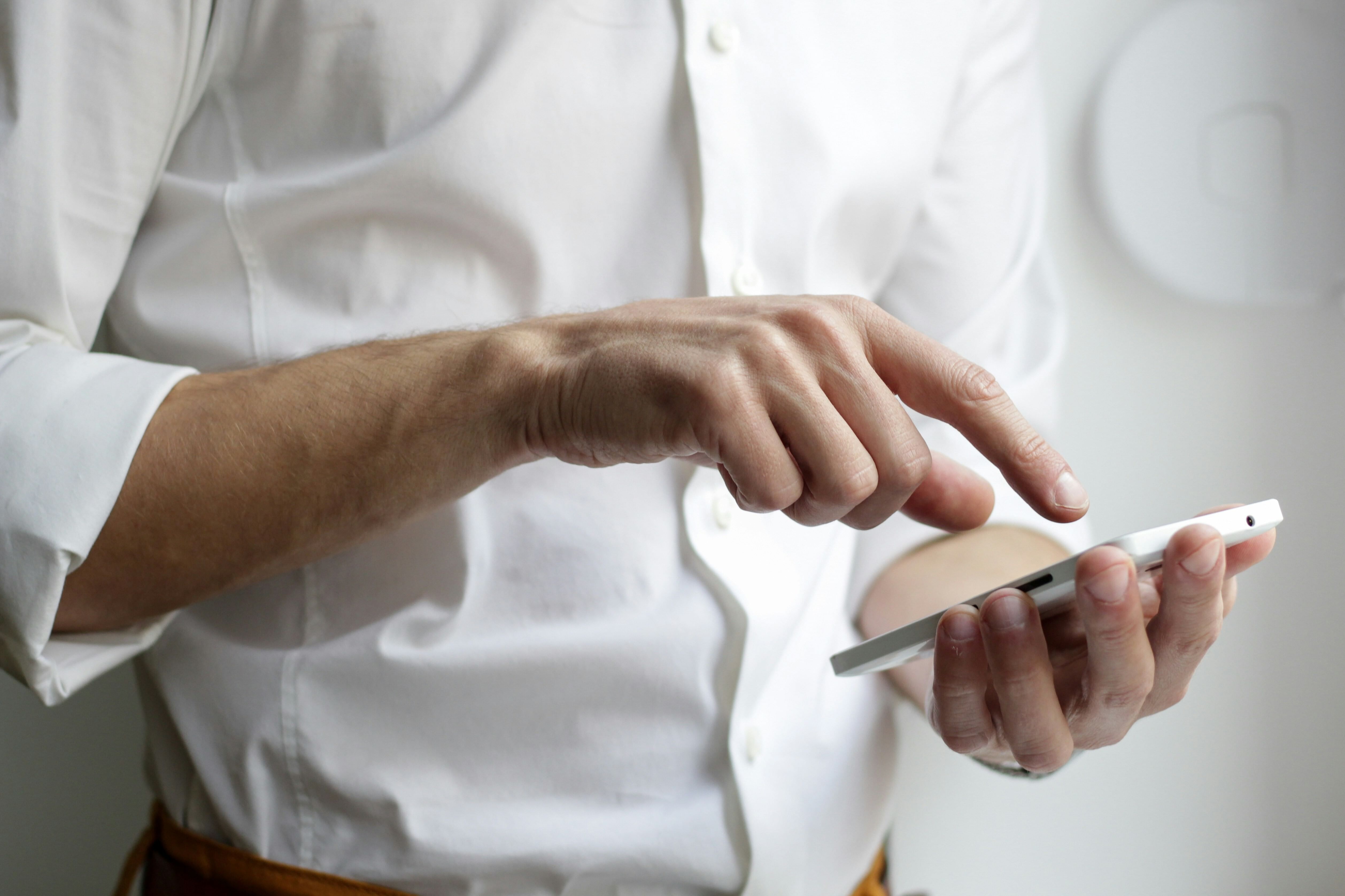 A man wearing a white shirt rejects a spam call on his phone