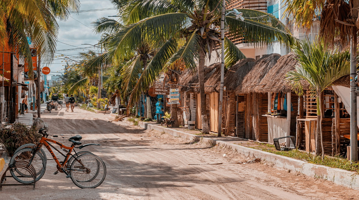 Dirt road lined with shops and palm trees in Mexico