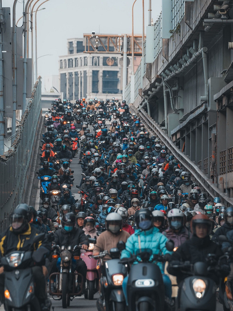 A cascading stream of scooters cresting over a hilly street in Taipei