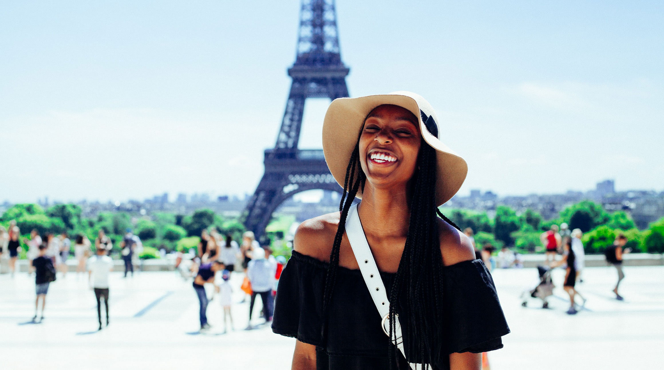 woman smiling in front of the eiffel tower in paris