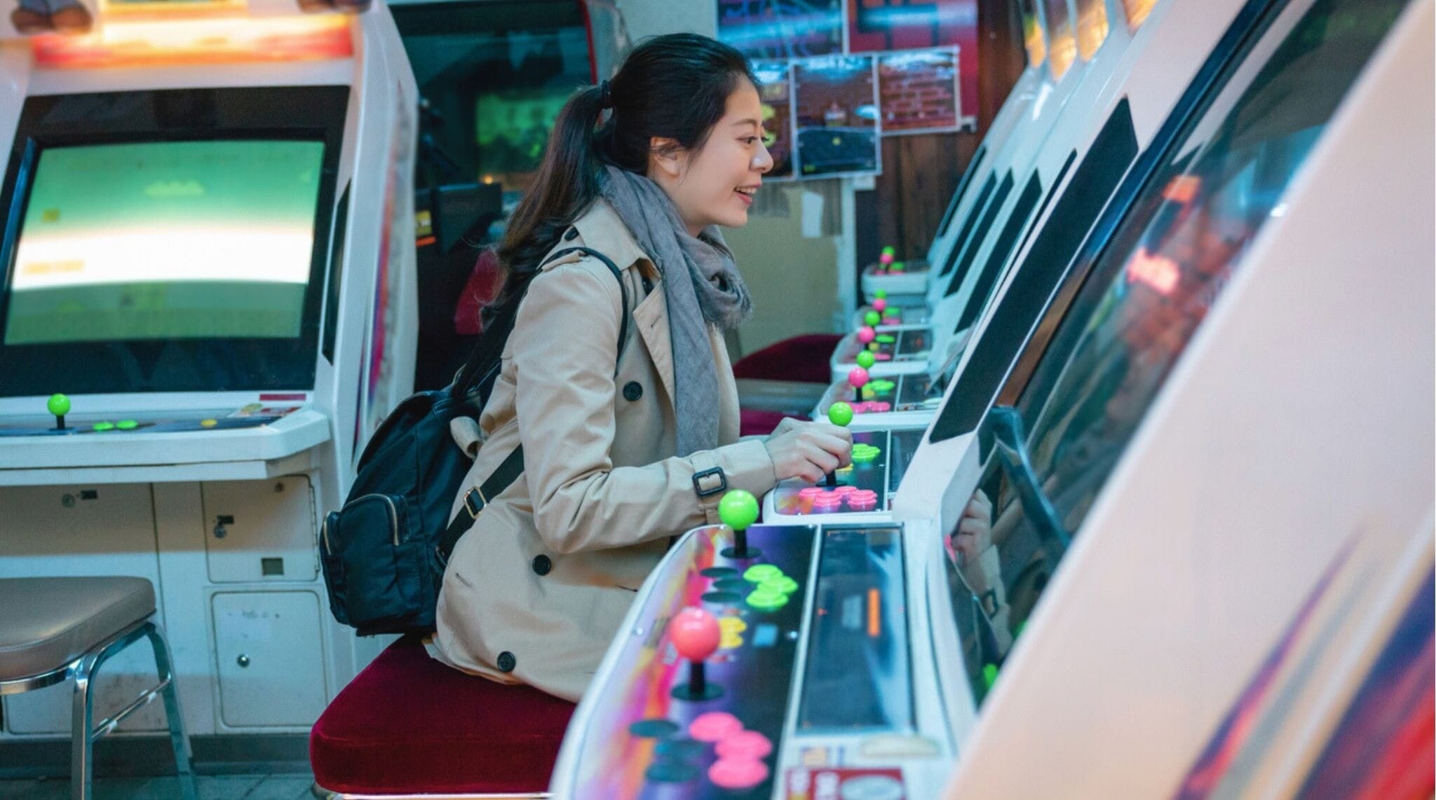 Mujer joven jugando emocionada en una máquina arcade en Japón.
