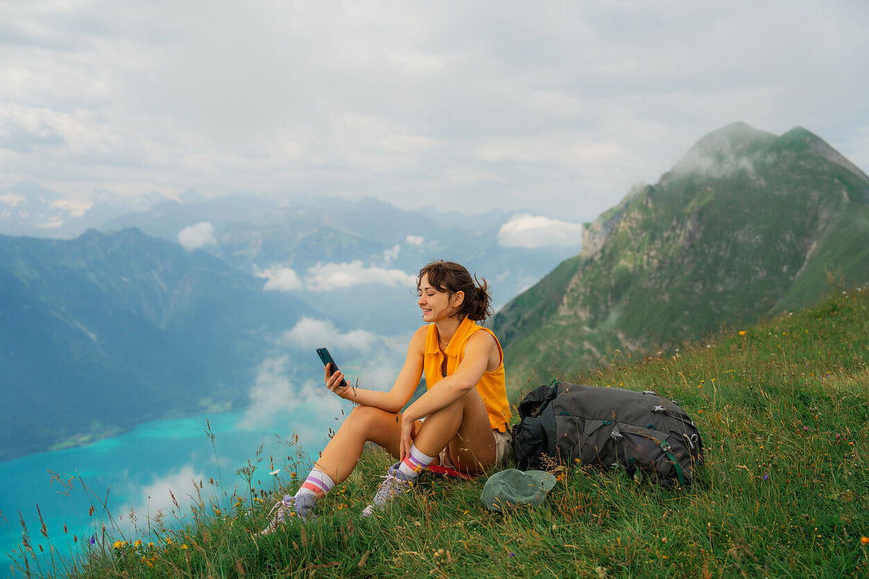 Frau mit Handy in der Schweiz auf einem Berg