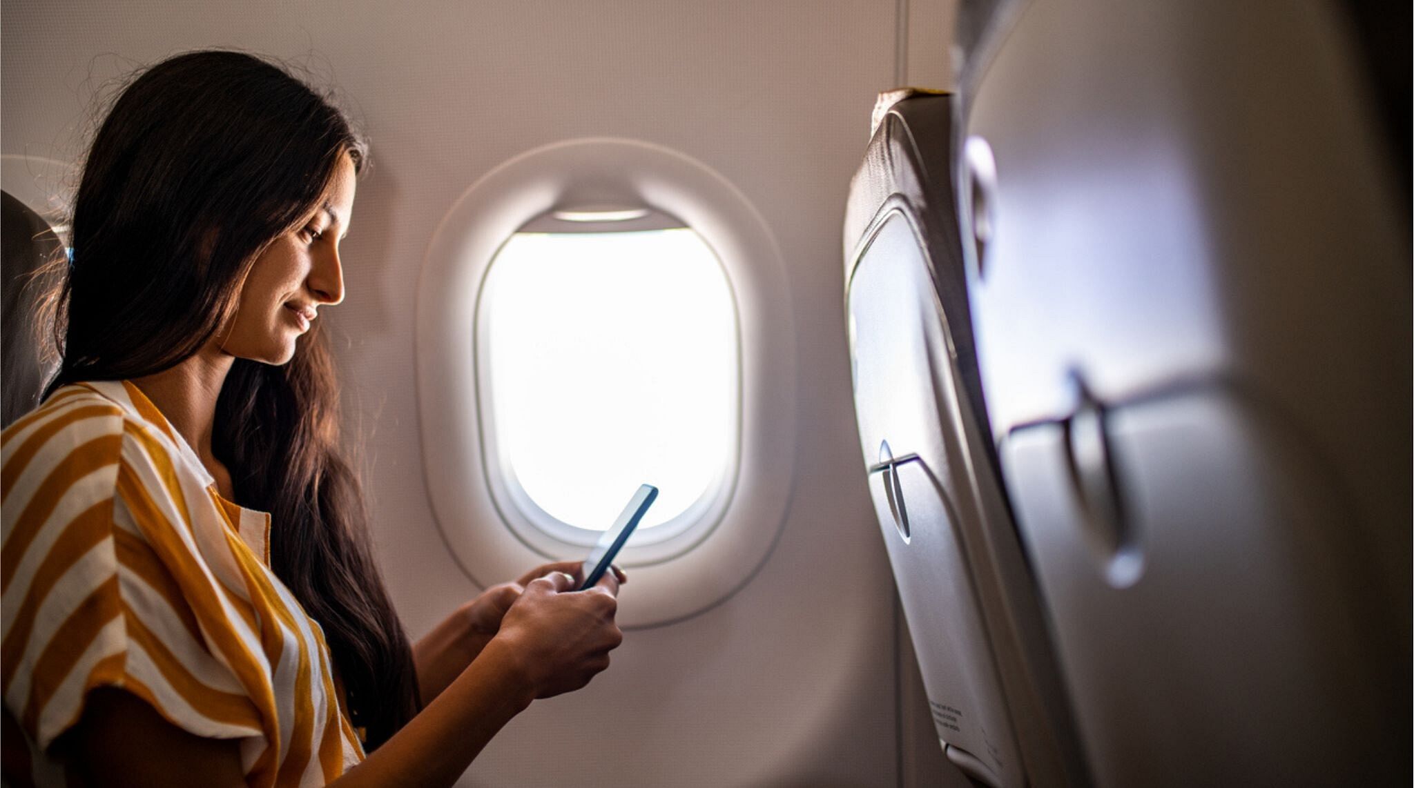 Janela de avião com vista para a asa e o céu, indicando viagem.