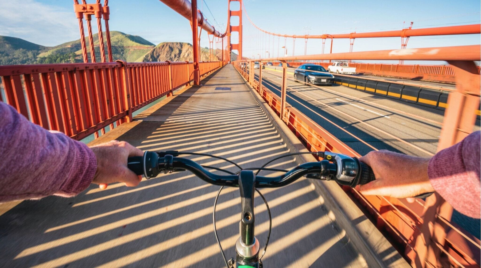 Persona cruzando el puente Golden Gate en bicicleta en San Francisco, con la bahía al fondo.