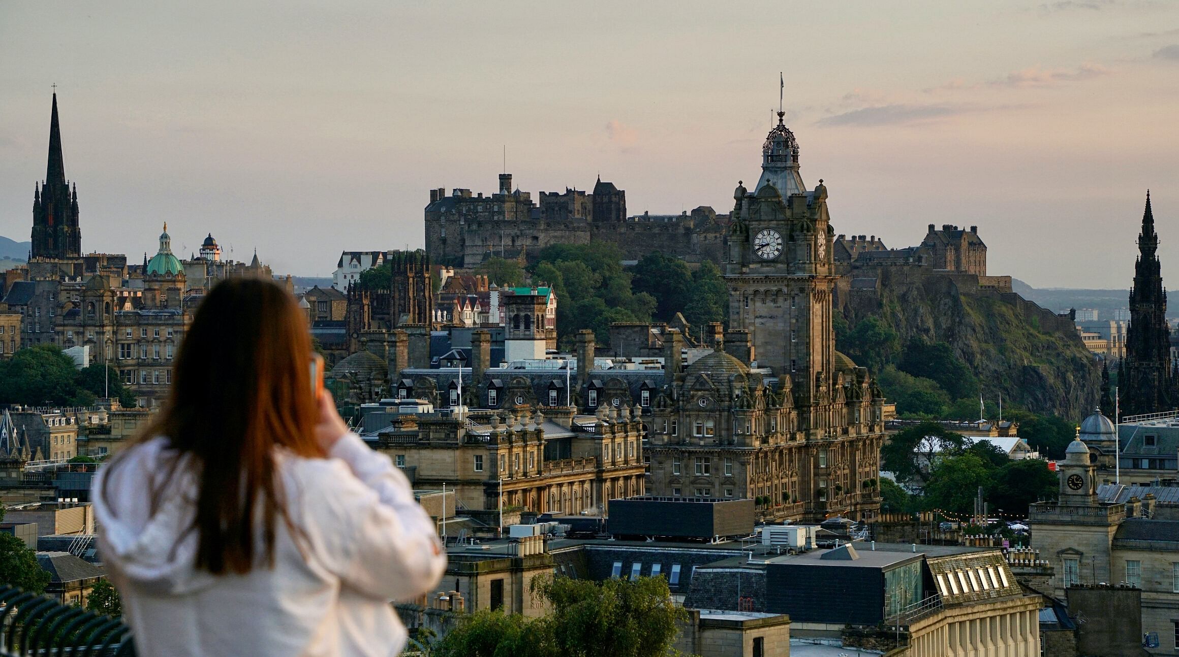 woman taking a photo of edinburgh skyline