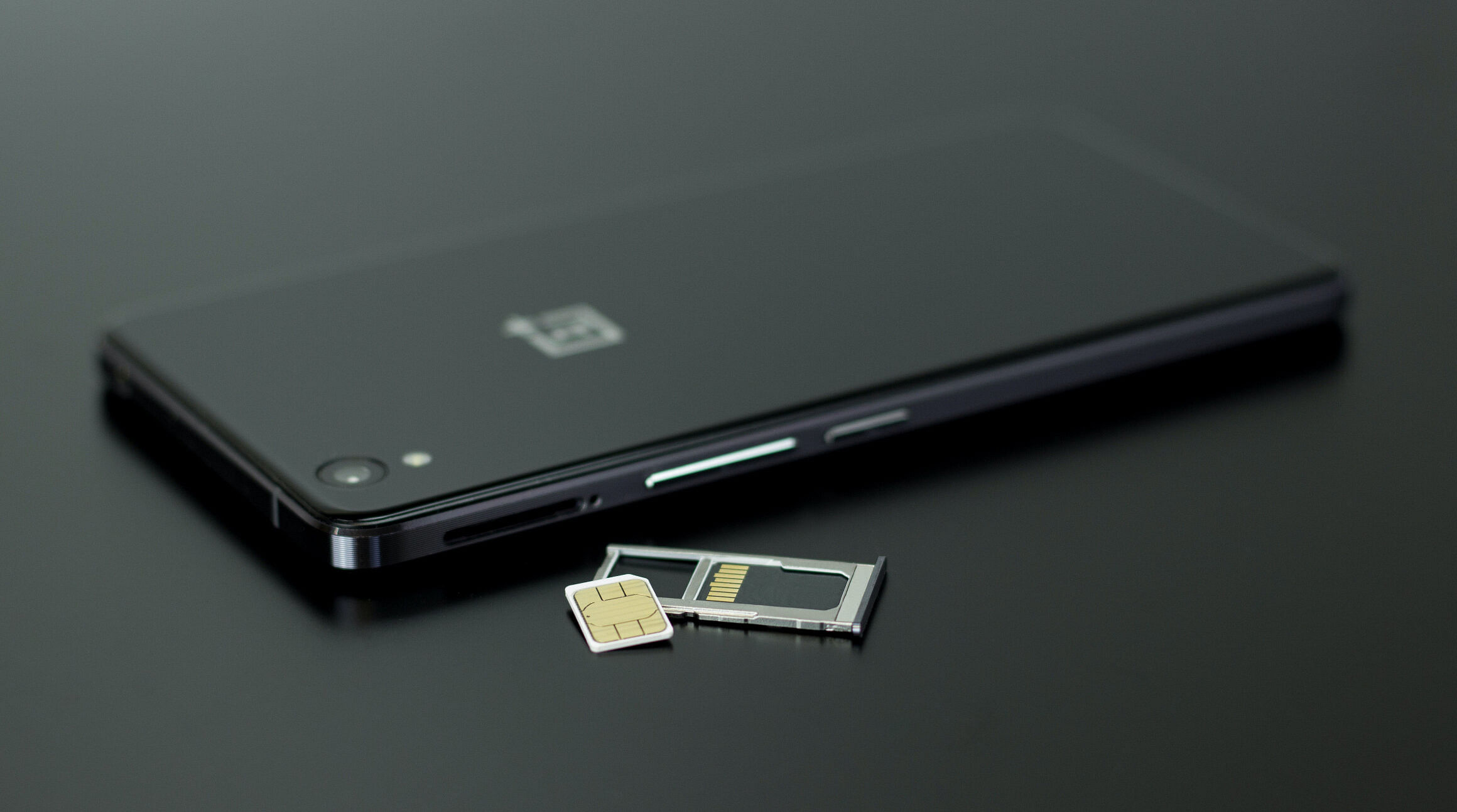 Akıllı telefonun yanında duran SIM kart ve SIM kart yuvası
