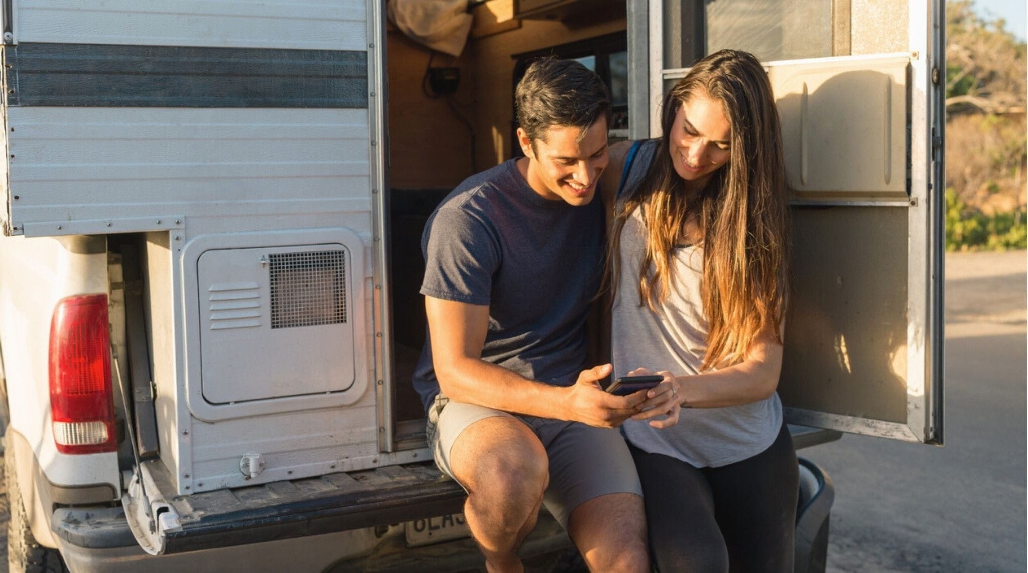 Pareja viajera descansando en su camper al atardecer cerca de San Diego.