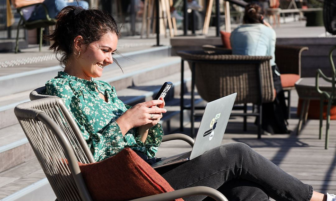 Girl sitting at an outdoor table and looking at her smartphone 