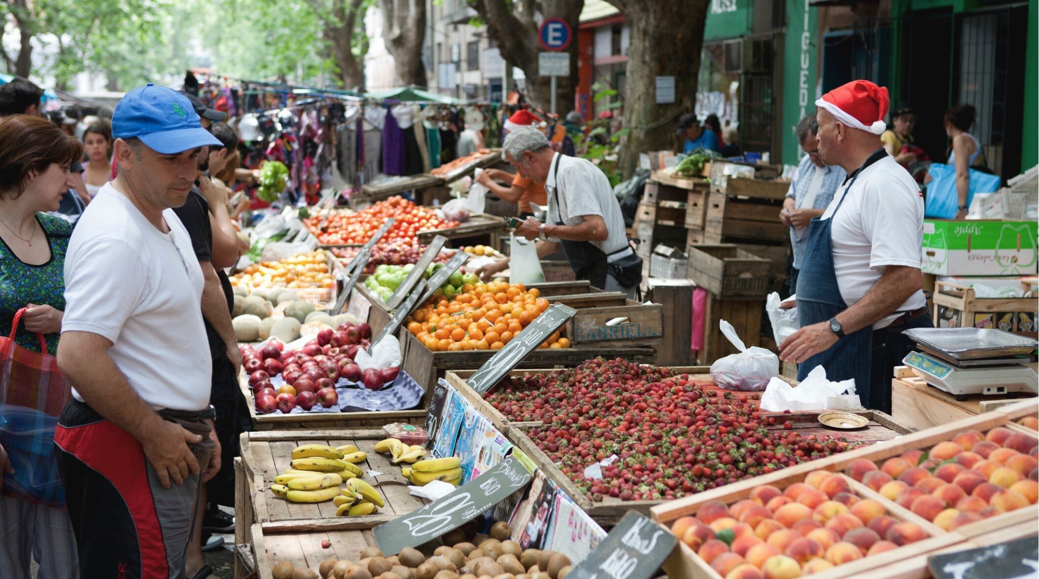 À medida que o Natal se aproxima, os trabalhadores das barracas do mercado usam gorros festivos de Natal enquanto vendem suas frutas e verduras aos clientes.
