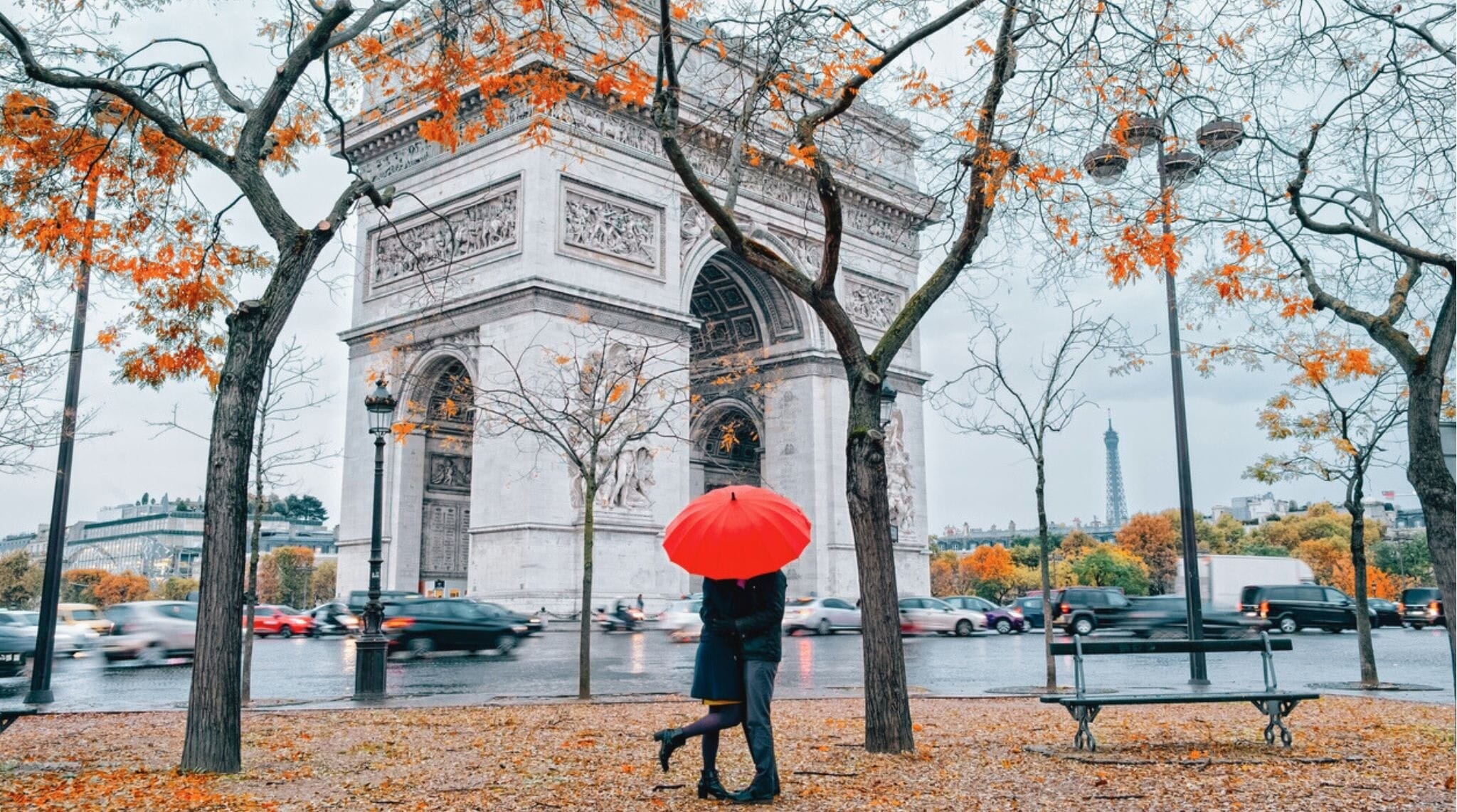 Pareja caminando bajo un paraguas durante un día lluvioso de invierno en París cerca de una calle adoquinada.