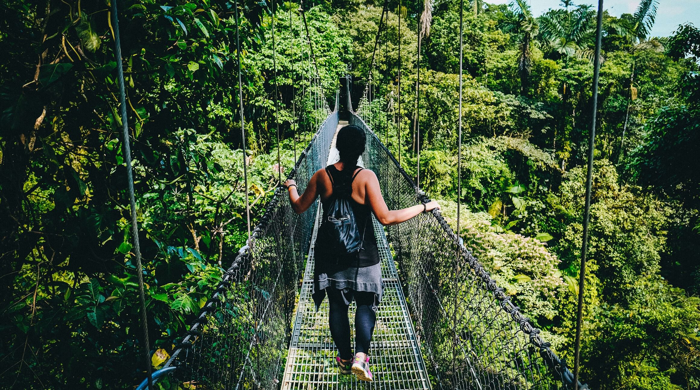 Woman walking on suspension bridge in Monteverde cloud forest