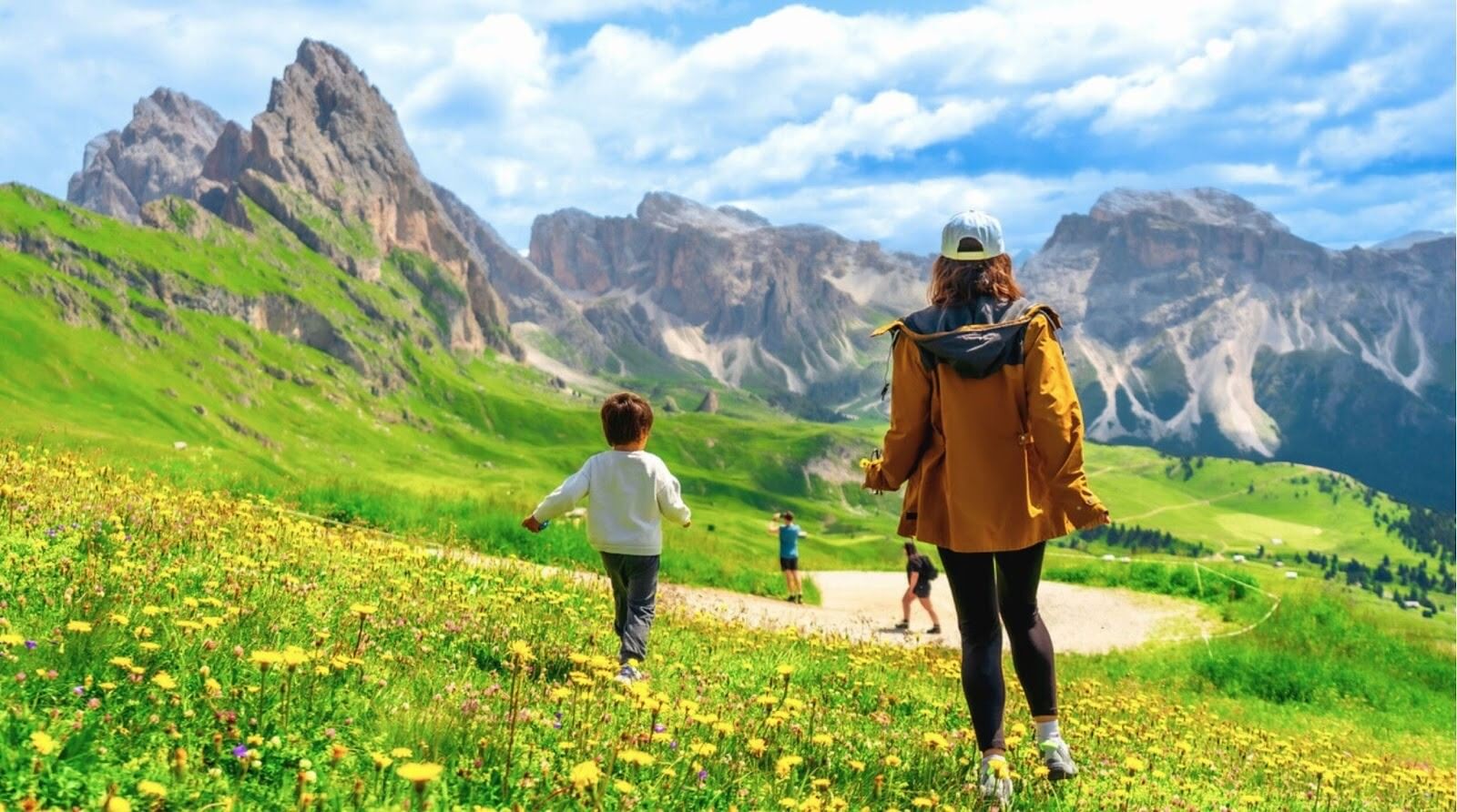 Turistas aproveitando um dia ensolarado de verão caminhando por campos de flores silvestres em Seceda, Dolomitas, Itália.