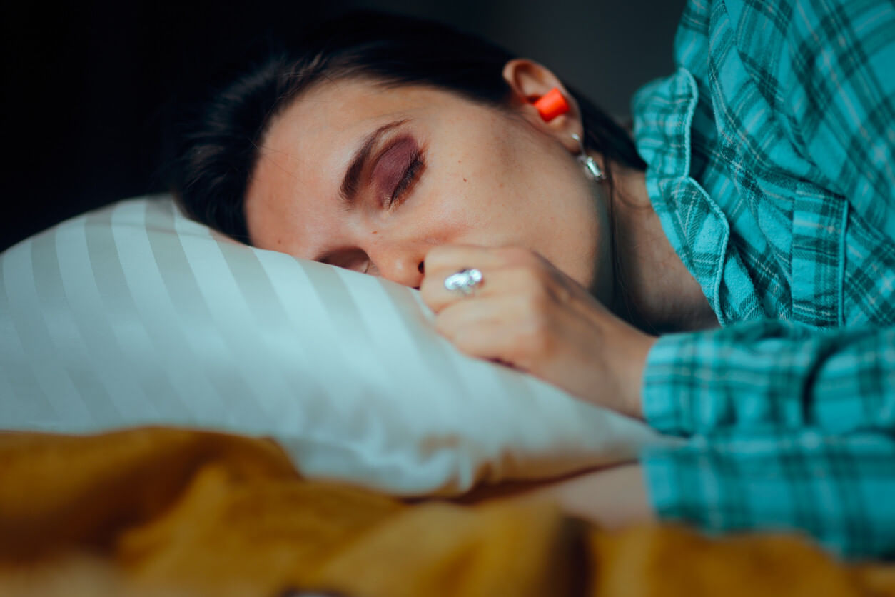 Woman in blue sleeping with earplugs in
