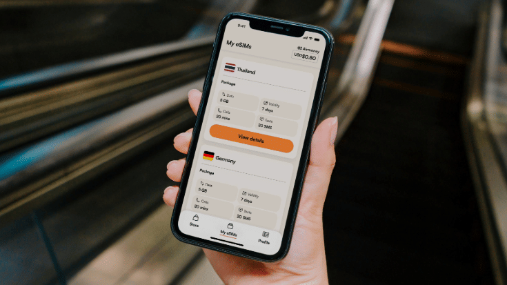 A colour photograph showing a close-up of a woman's hand holding a black mobile phone. On the phone screen, it shows the Airalo travel eSIMs app, with the option of buying an eSIM for Germany displayed. To illustrate a blog post entitled 'Berlin Half Marathon 2026: Can You Still Register?'