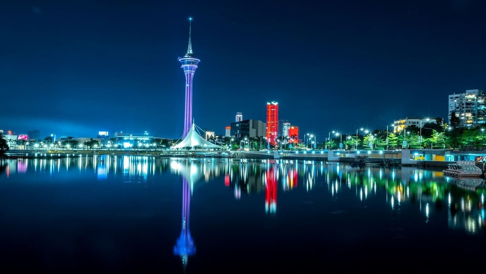 A night view of a city across the water with the Macau Tower in sight