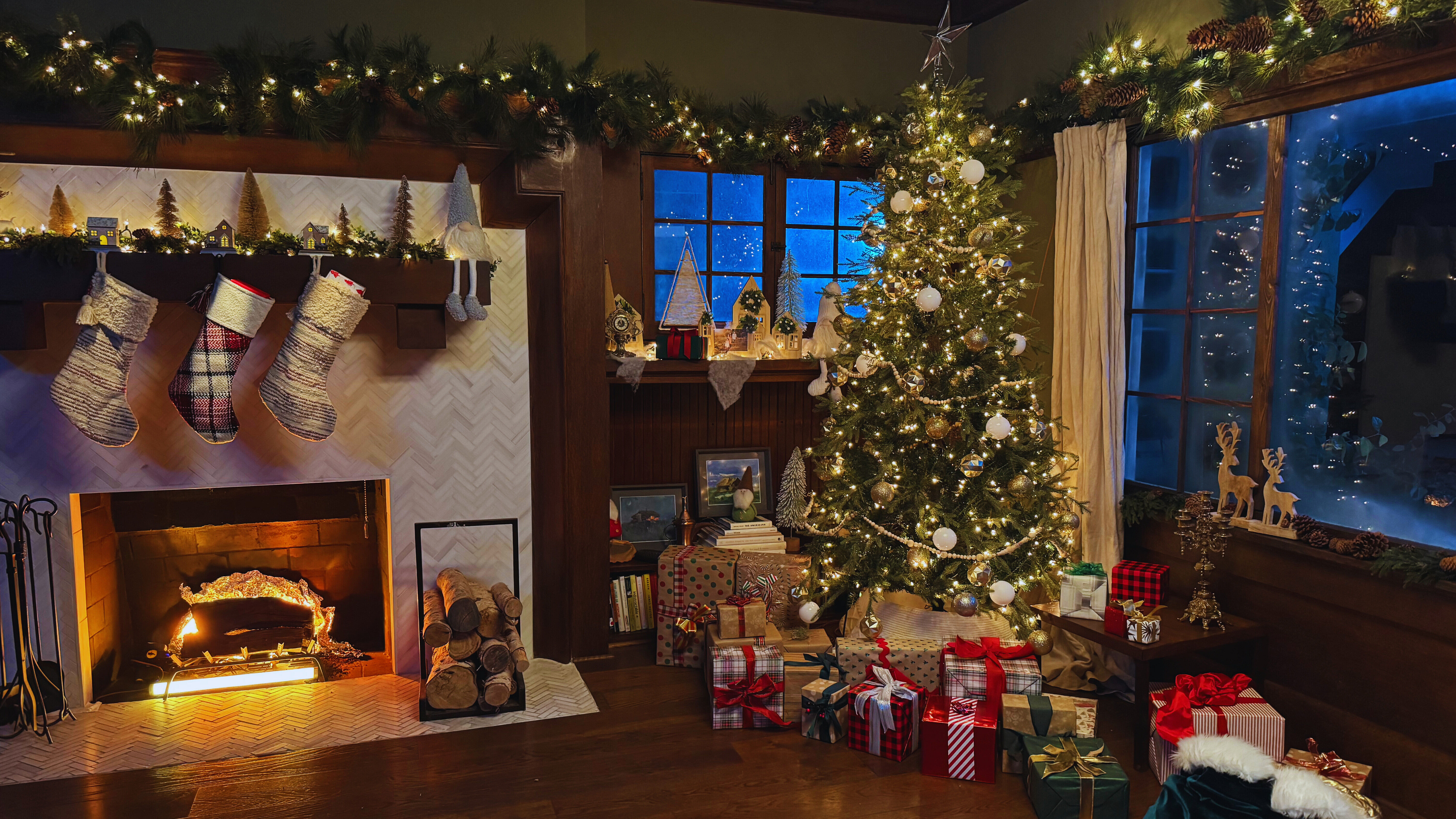 A cozy Christmas scene complete with a tree, presents, stockings, and a fake fire created with multicolored lights