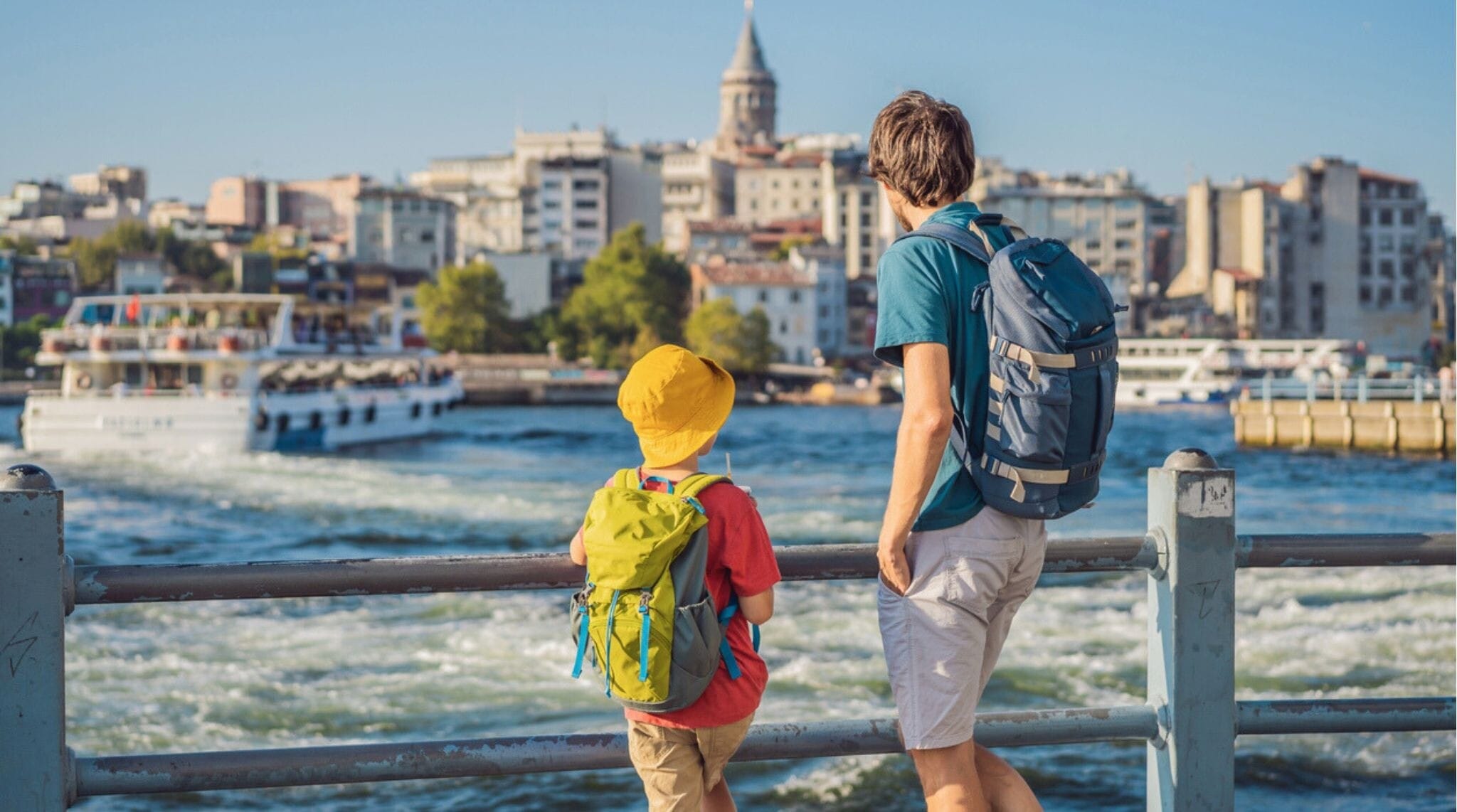 Pai e filho turistas apreciam o horizonte de Istambul, na Turquia. Distrito de Beyoğlu com casas antigas e a Torre de Gálata ao topo, vista a partir do Chifre de Ouro.