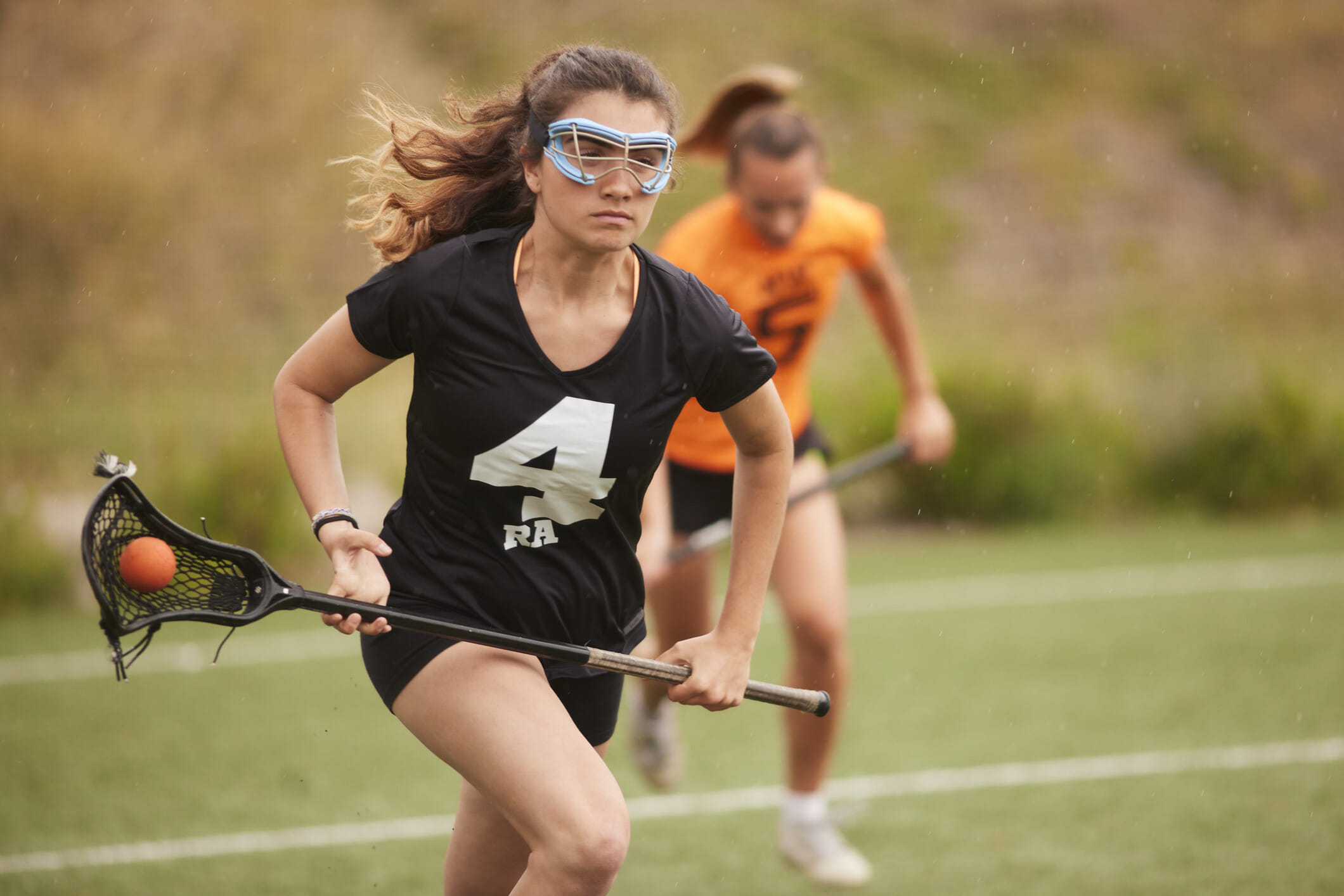 Two female lacrosse players on the field