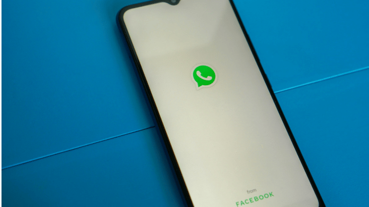 A smartphone showing the WhatsApp Messenger loading screen with the green logo on a teal background. Perfect visual for a blog about WhatsApp text tricks like italics in WhatsApp, bold text for WhatsApp, and how to do strikethrough on WhatsApp.