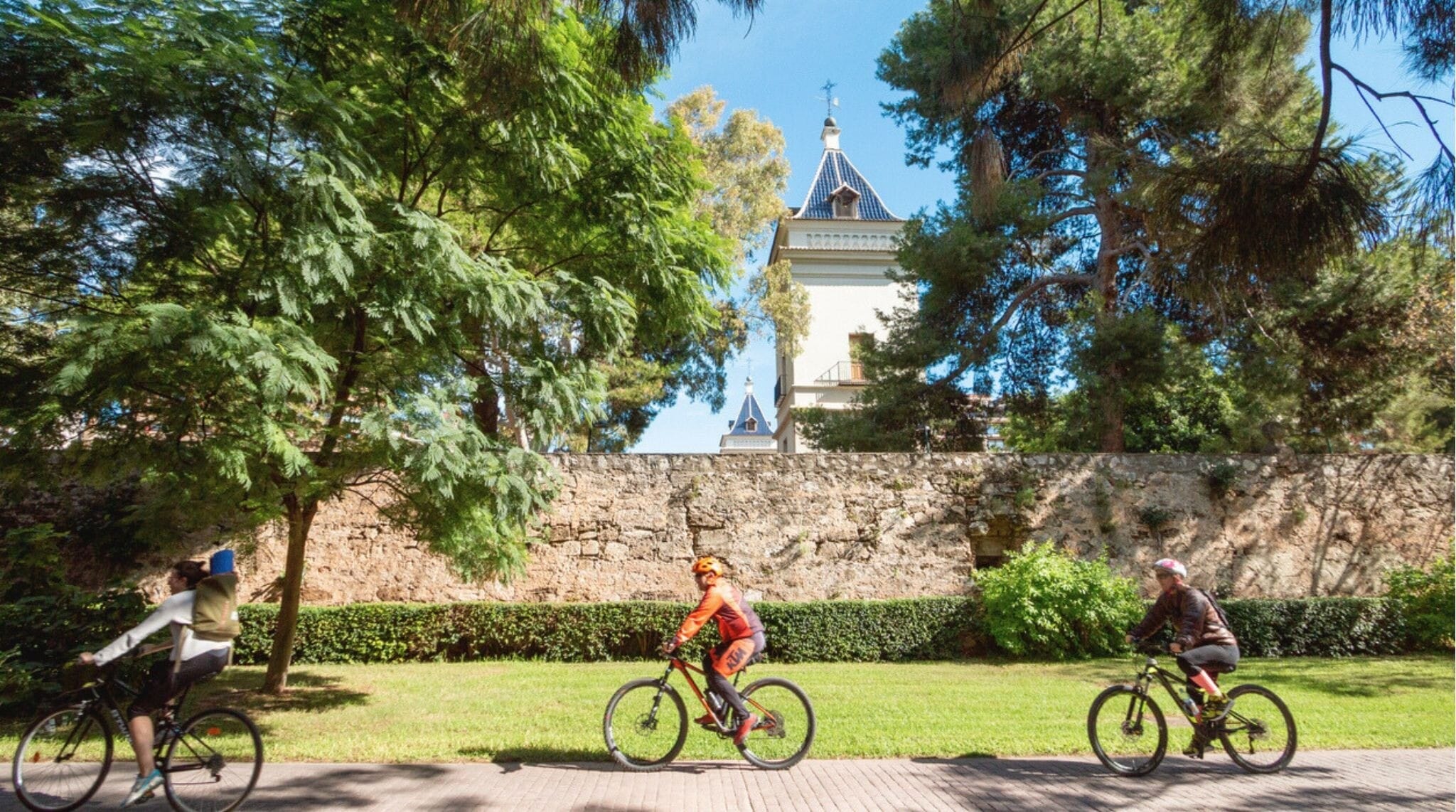 Ciclistas pedalando pelos Jardins do Rio Túria, em Valência, Espanha.