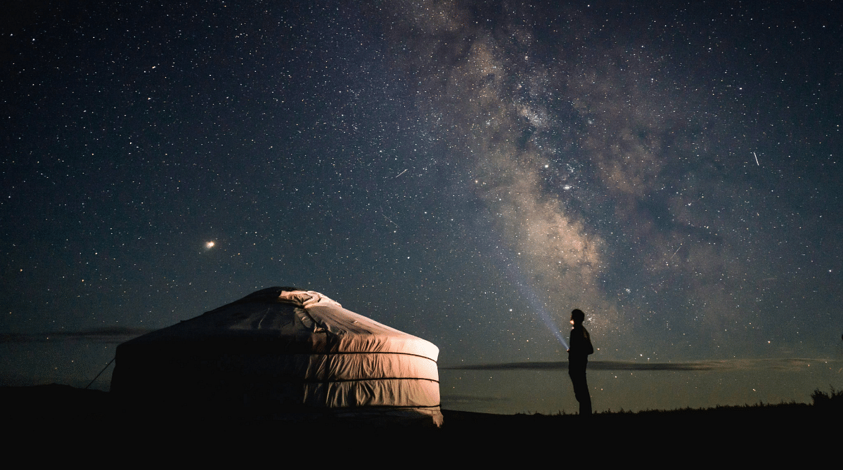 Traveler outside a yurt looking at the Milky Way