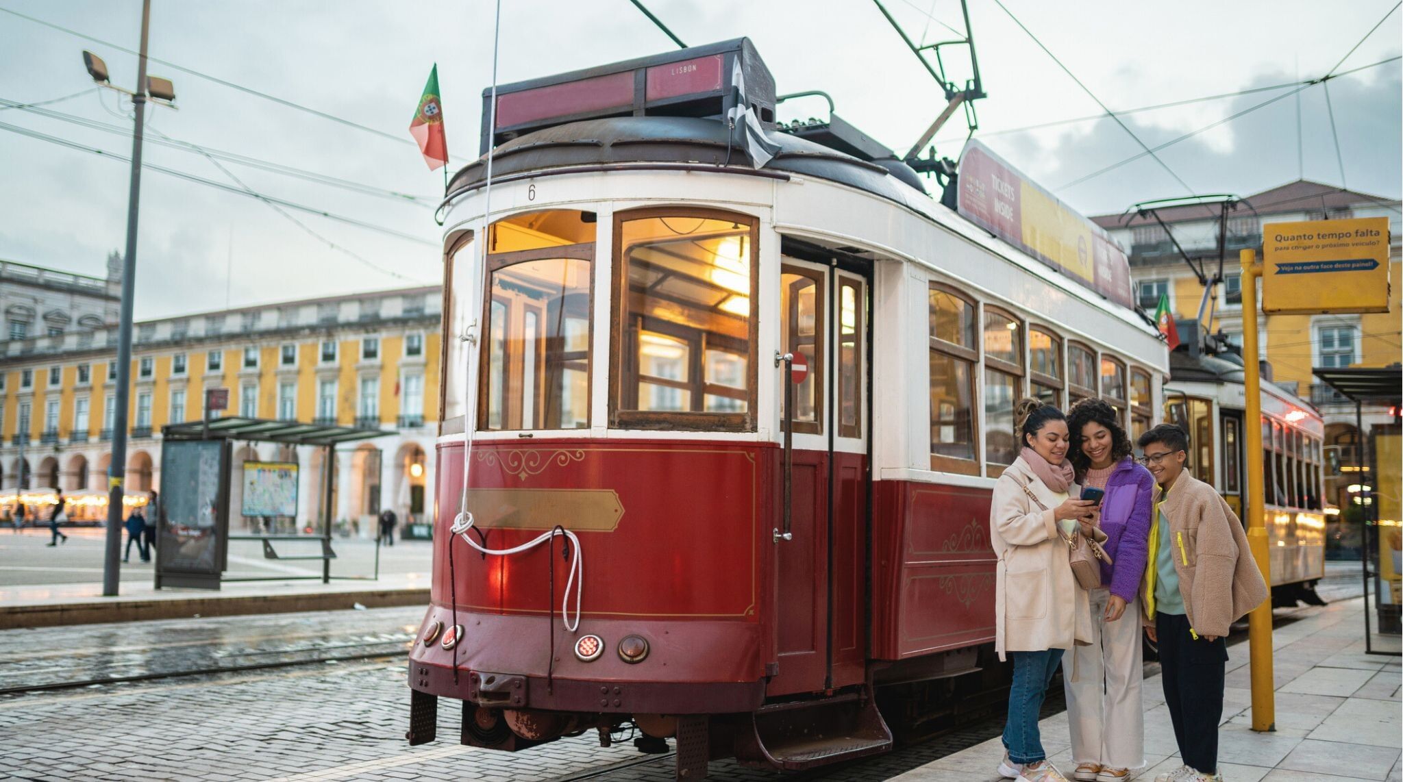 Família posando ao lado de um Tram na praça do Comércio em Lisboa.