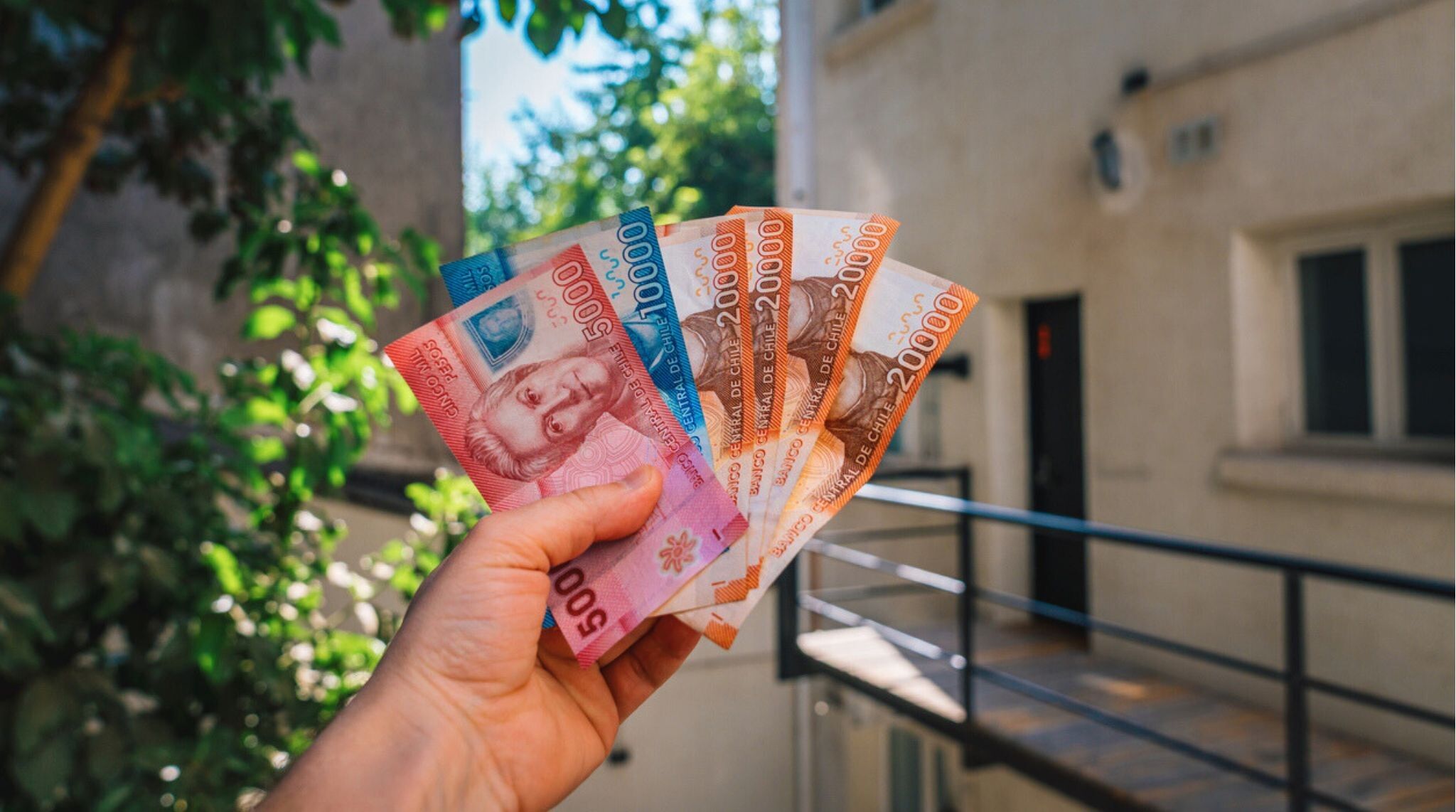 Qual moeda levar para o Chile: mão de turista segurando cédulas de peso chileno nas ruas de Santiago, Chile.