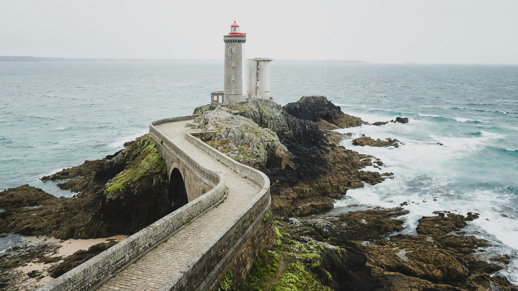 A rugged coastline in Brittany, France, featuring an old lighthouse