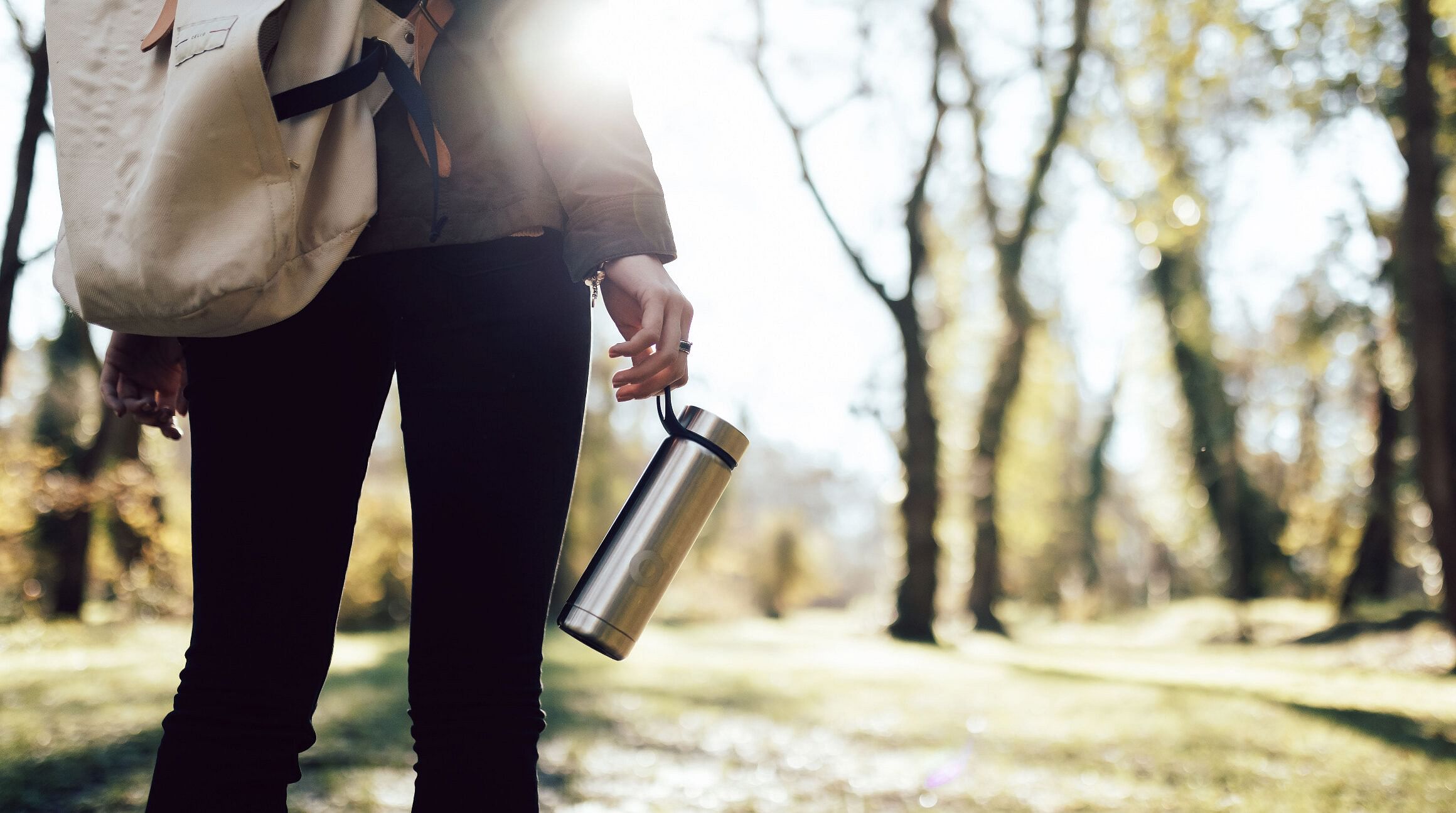 woman hiking and holding a reusable water bottle