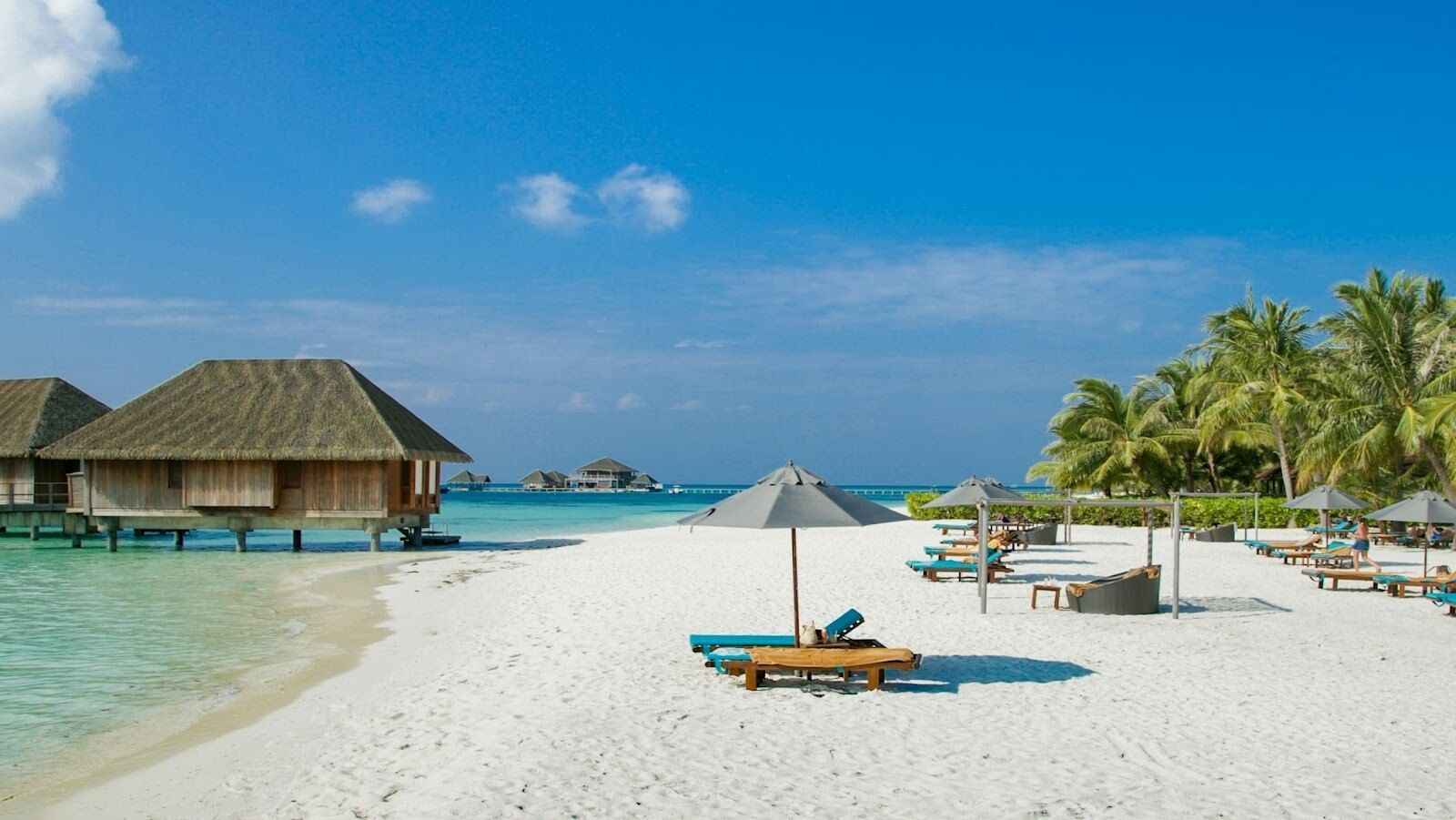 Beach view with blue skies, white sands, trees and umbrellas