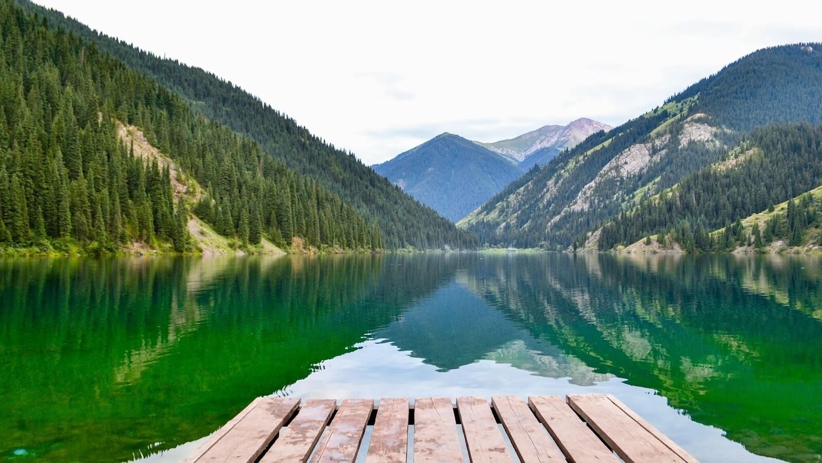 Brown wooden panel on a body of water, with trees and mountains surrounding