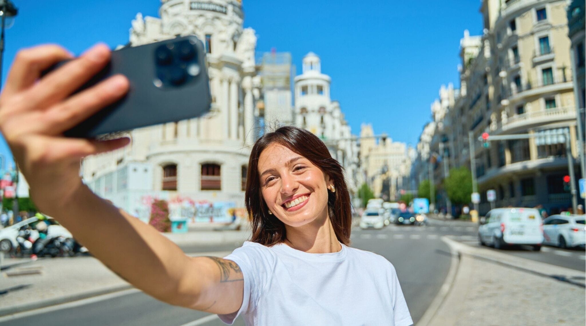 Turista tomando selfie en la Gran Vía de Madrid con su celular.]